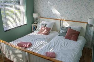 Farmhouse Lodge Giethoorn في خيتهورن: غرفة نوم بسريرين عليها مخدات