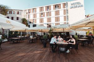 un grupo de personas sentadas en una mesa en un patio en Hotel Jadran Šibenik, en Šibenik