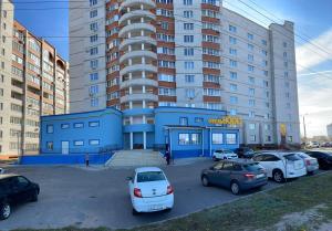 un estacionamiento con autos estacionados frente a un edificio en Hotel Nord, en Voronezh