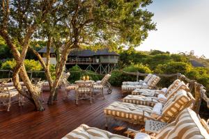 una terraza con sofás, mesa y sillas en Lalibela Game Reserve Tree Tops Safari Lodge, en Paterson