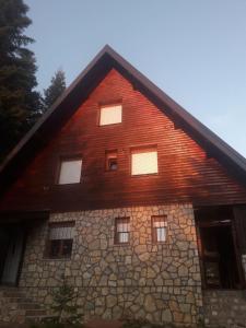 a large wooden house with a stone wall at APARTMANI Arsic in Jahorina