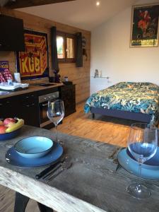 Cette chambre comprend une table avec deux verres et un lit. dans l'établissement Gîte à broc à 5 minutes de Plombières les Bains, à Plombières-les-Bains