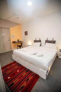 a large white bed in a room with a red rug at Nomads Hotel Petra in Wadi Musa