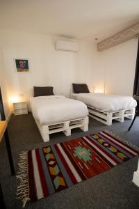 two white beds in a room with a rug at Nomads Hotel Petra in Wadi Musa