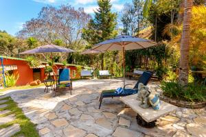 a patio with two umbrellas and a teddy bear on a bench at Pousada Villa 3 Lagos in Santo Antônio do Pinhal