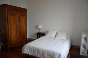 a bedroom with a white bed and a wooden cabinet at LA MAISON DU DIRECTEUR DE SALIN DE GIRAUD in Salin-de-Giraud