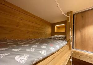 una camera con un letto su una parete in legno di Les Balcons de Valloire a Valloire