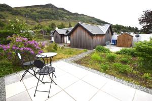 d'une terrasse avec une table et des chaises dans le jardin. dans l'établissement Arivean Cottage, à Lochgoilhead