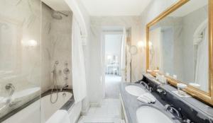 a bathroom with a tub, sink and mirror at Hôtel Hermitage Monte-Carlo in Monte Carlo