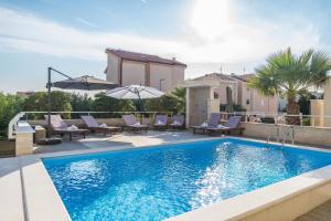 - une piscine avec des chaises et des parasols à côté d'une maison dans l'établissement Apartments & Rooms Danivan Pool Villas B, à Novalja