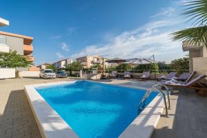 - une piscine avec des chaises longues à côté d'une maison dans l'établissement Apartments & Rooms Danivan Pool Villas B, à Novalja