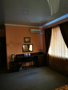 ネフテカムスクにあるОтель "ОСКАР"のデスク、鏡、窓が備わる客室です。