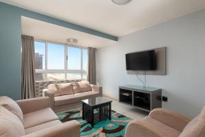 een woonkamer met 2 banken en een flatscreen-tv bij Lancaster Gate Apartment in Durban