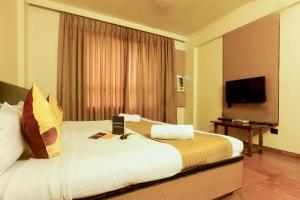 Habitación de hotel con cama grande y TV en Celebrations Inn Pune, en Pune