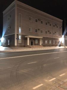 una calle vacía delante de un edificio por la noche en Hotel Bereke en Atyraū