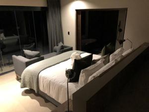1 dormitorio con 1 cama blanca grande y 1 silla en Luxury Villa looking onto Kruger National Park, en Belfast