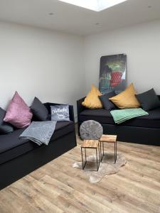 ein Wohnzimmer mit zwei schwarzen Sofas und bunten Kissen in der Unterkunft Gästewohnung Mönchengladbach in Mönchengladbach