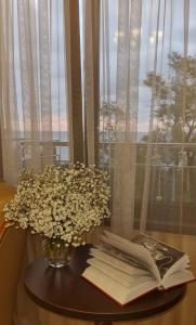 una mesa con un libro y un jarrón de flores en Marianna, en Adler