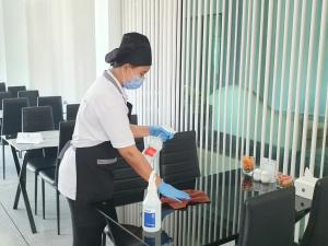 a woman in a room with a bottle of cleaner at Hotel Chuan Chom The High Resort Saraburi - SHA Plus in Sara Buri