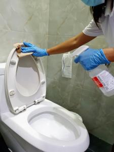 a woman in blue gloves is cleaning a toilet at Hotel Chuan Chom The High Resort Saraburi - SHA Plus in Sara Buri