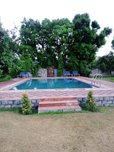 a swimming pool with a stone wall around it at Lohana Village Resort in Pushkar