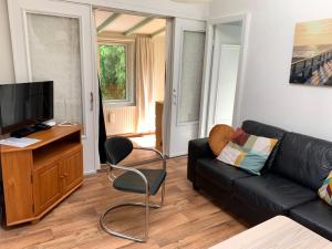 a living room with a black couch and a television at JuRia Zonlicht in Renesse