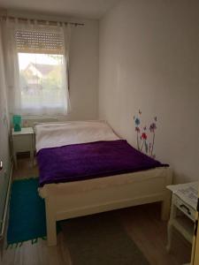 um quarto com uma cama com um edredão roxo e uma janela em ivana 2 em Belišće