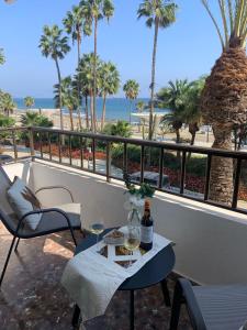 a table with a bottle of wine on a balcony with the beach at Apartamento frente a la playa Piso 2 in Estepona
