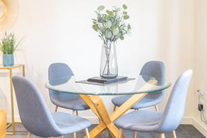une table en verre avec des chaises bleues et un vase avec des fleurs dans l'établissement Charming Westend/City centre Apartment, à Glasgow