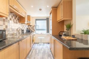 a kitchen with wooden cabinets and black counter tops at Charming Westend/City centre Apartment in Glasgow