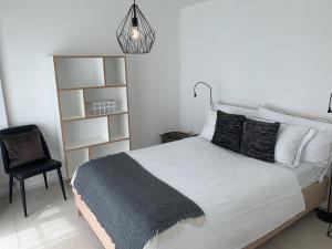 una camera da letto con un letto bianco con una coperta nera e una sedia di Zürich Niederdorf - Grossmünster a Zurigo