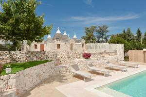 une maison avec un mur en pierre et une piscine dans l'établissement Trulli Colebè con Piscina, à Martina Franca