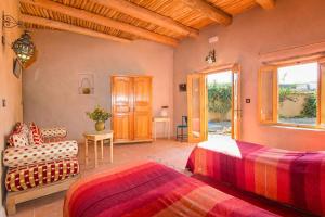 a bedroom with two beds and a couch and a window at La Maison Anglaise Garden Ecolodge in Taroudant