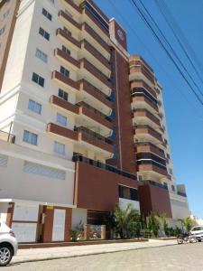 ein hohes Gebäude mit einem davor geparkt in der Unterkunft Apartamento Completo Família Gravata Navegantes SC Beto Carreiro in Navegantes