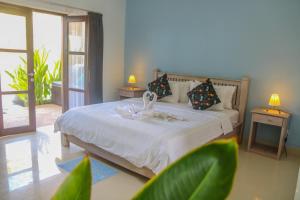 a bedroom with a bed with two swans on it at Divine Divers Gili Meno in Gili Meno