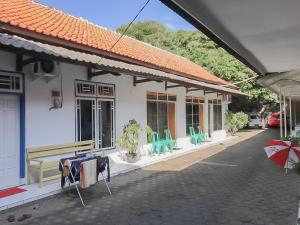 uma casa com cadeiras, uma mesa e um guarda-sol em RedDoorz near Pantai Barat Pangandaran 2 em Pangandaran