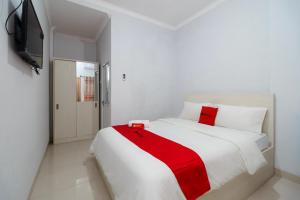 a white bedroom with a red blanket on a bed at RedDoorz near Pantai Barat Pangandaran 2 in Pangandaran