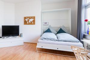 Helle Wohnung in TOP-Lage, Hasselbachplatz - Altstadt, W-LAN, 4 Schlafplätze في ماغدبورغ: غرفة نوم بيضاء مع سرير وتلفزيون