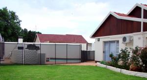 una valla frente a una casa con piscina en 17 on 13th en Edenvale