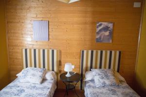 Duas camas num quarto com paredes de madeira em EL VENERO DE MOSTOLES em Constantina