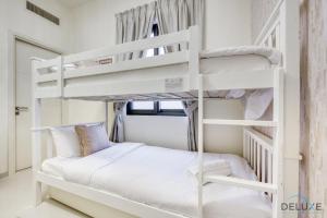 a bedroom with white bunk beds in a room at Extensive 3BR Townhouse at Janusia Damac Hills 2 by Deluxe Holiday Homes in Dubai +43 photos
