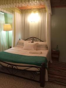 ein Schlafzimmer mit einem Himmelbett und weißen Kissen in der Unterkunft Palm Airport Suites in Nairobi