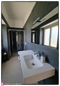 een badkamer met een witte wastafel en een spiegel bij Alta Area in Nova Siri