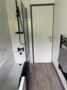 a bathroom with a white tub and a shower at 4 bedroom bungalow in peaceful countryside with log burner - Talar Deg, Capel Madog in Bow Street