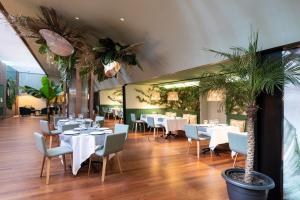 a restaurant with white tables and chairs and palm trees at Aparthotel Atenea Barcelona in Barcelona