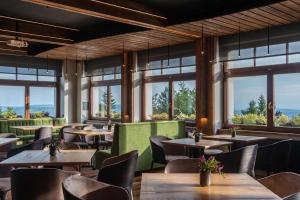 a restaurant with tables and chairs and windows at Hotel Královka in Bedřichov
