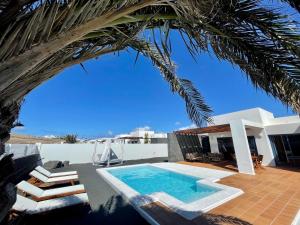 a house with a swimming pool and a palm tree at Villalia Isora in Playa Blanca