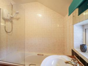 a bathroom with a shower and a tub and a sink at Cloud View Cottage in Ashbourne