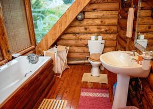 a bathroom with a toilet and a tub and a sink at Stanford Lake lodge in Haenertsburg