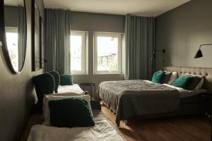 a bedroom with two beds and two windows at Hasse på Sjökanten Hotell & Restaurang in Jönköping